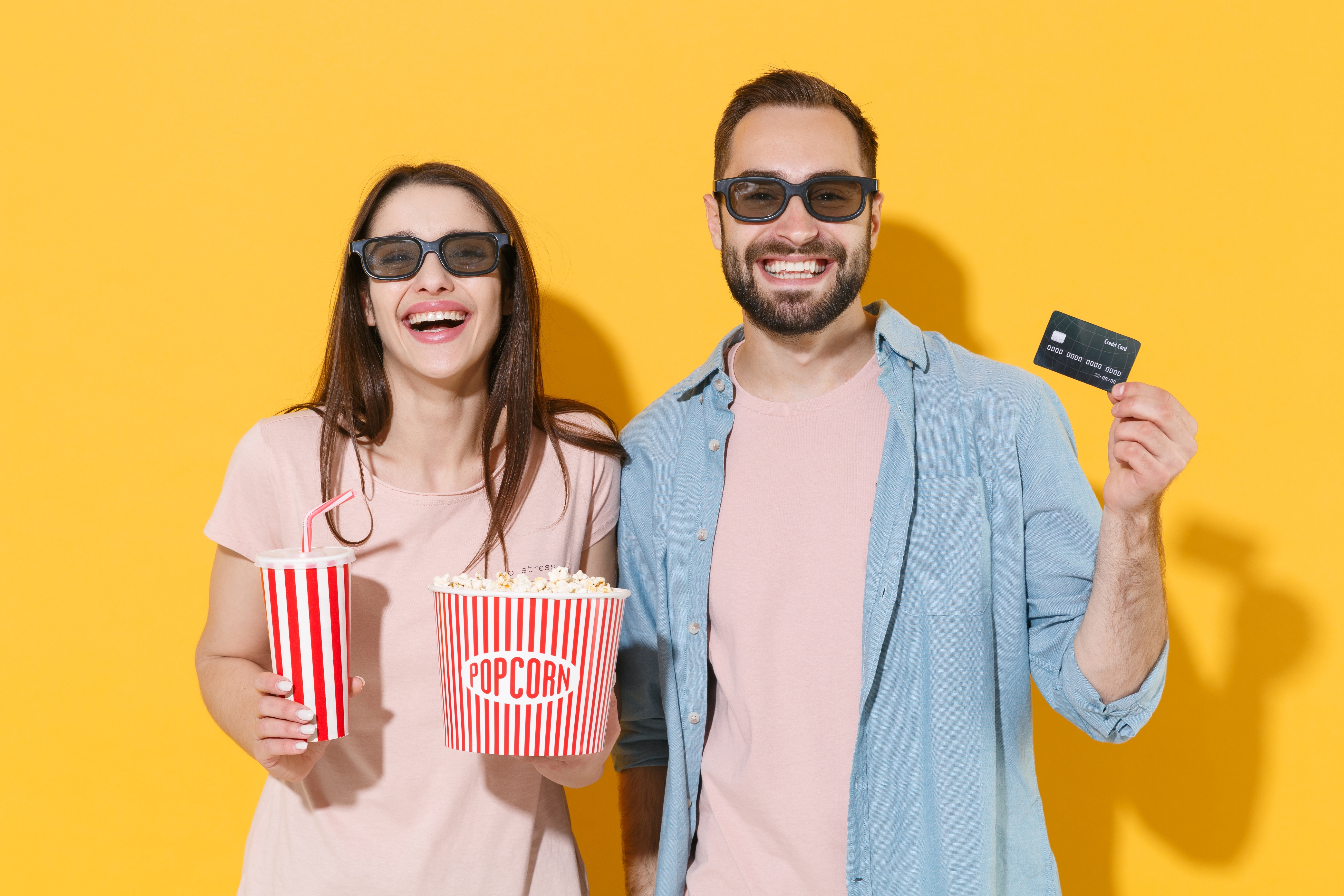 two moviegoers with credit card and pop corn in hand